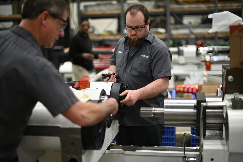 Milacron team members working with a machine