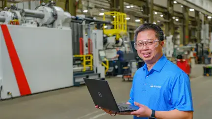 Milacron employee holding his laptop in warehouse