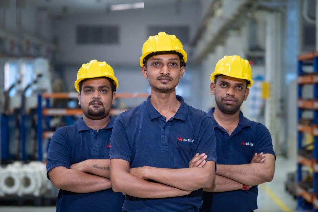 Three team members standing together with yellow hard hats on
