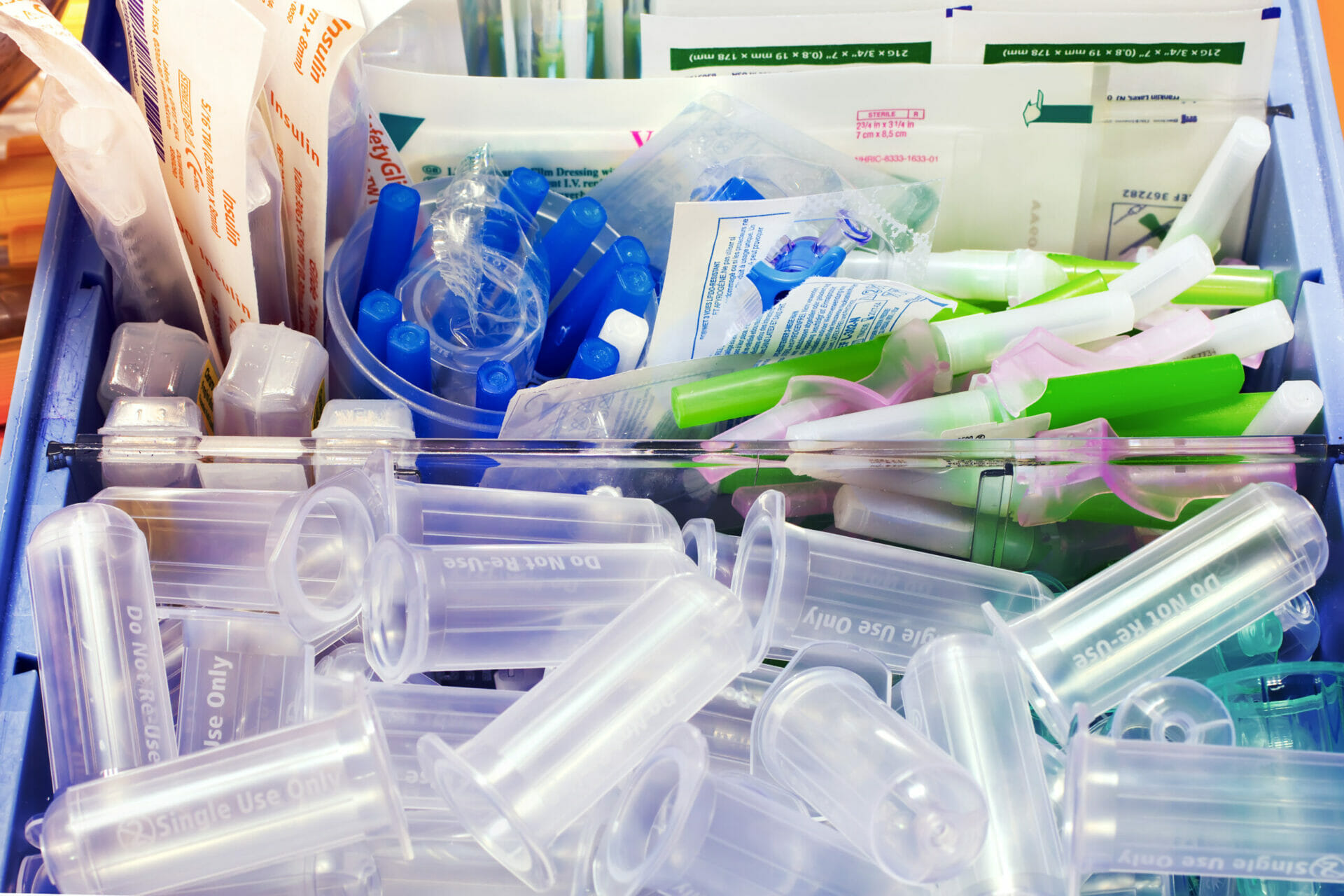 Various medical supplies like syringe tubes and wipes in a tub